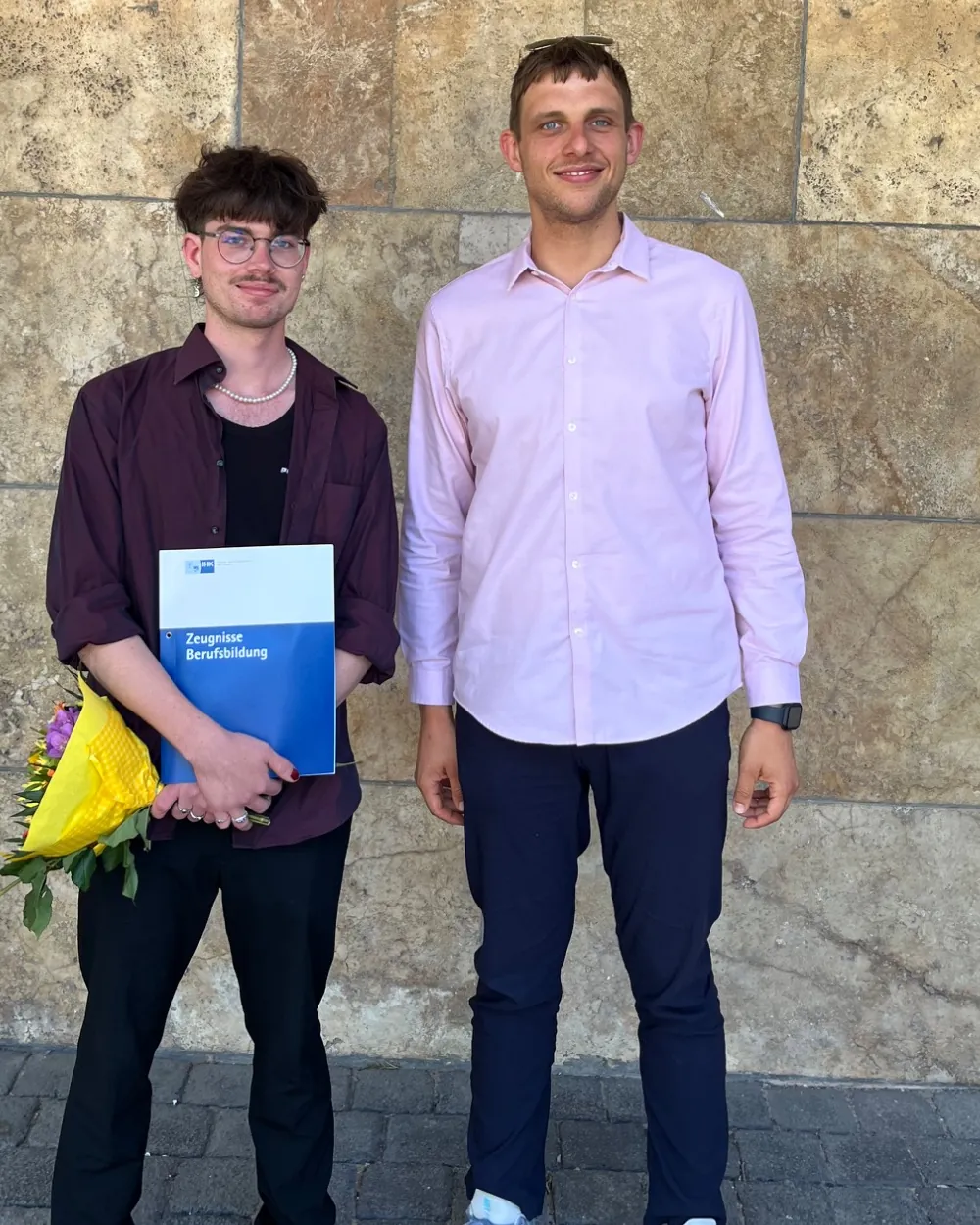 Peter Maibaum neben einem frisch ausgelernten Chemielaboranten mit Zeugnis und Blumen