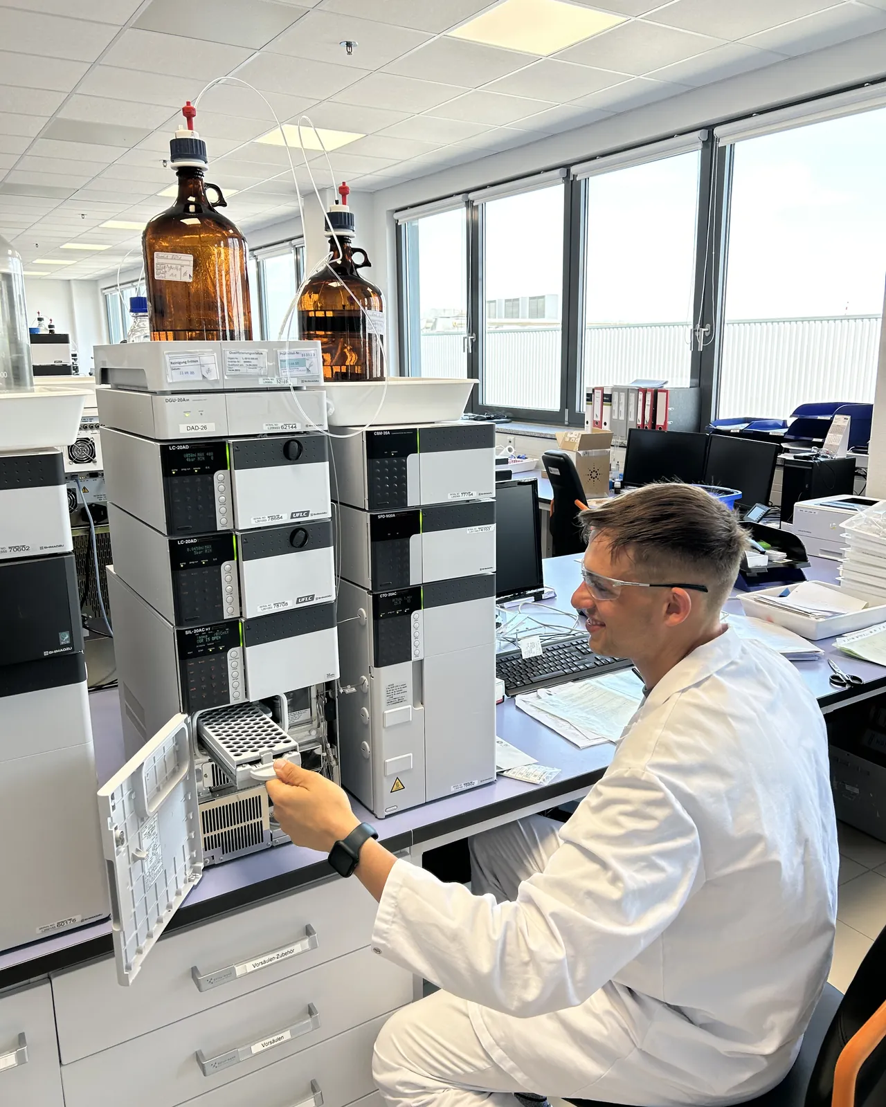 Peter Maibaum sitzt im Analytiklabor am Autosampler einer HPLC-Anlage