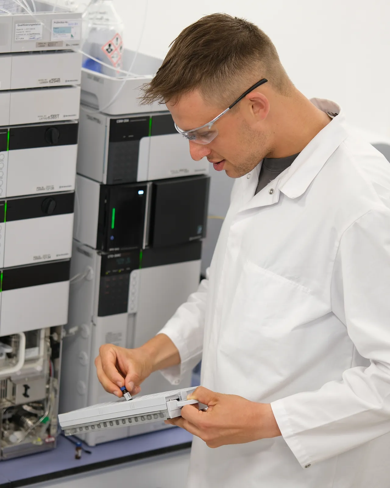 Peter Maibaum mit Schutzbrille an einer HPLC-Anlage, ein Bauteil in der Hand